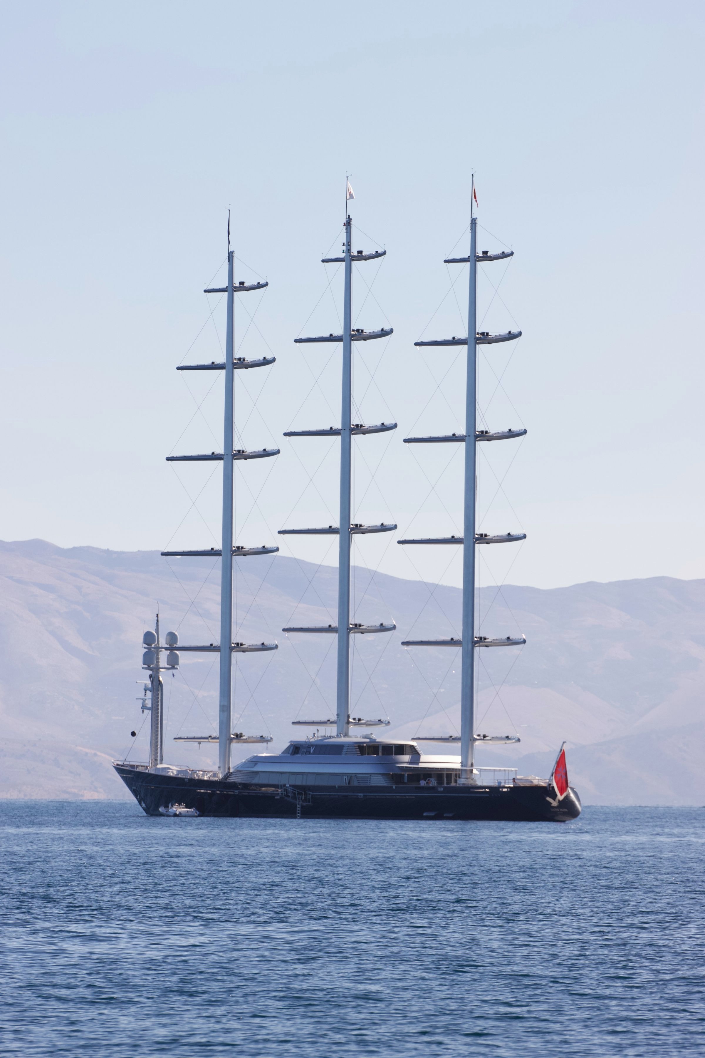 A yacht anchored in a calm Mediterranean bay at golden hour